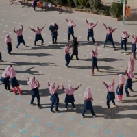 A group of schoolgirls, including refugees attending school for the first time, play in a circle in the playground