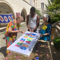 People work on a banner that says "Feliz Dia De Africa"