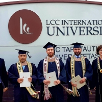 Students smile at the camera. They are holding their diplomas and are wearing graduations caps and gowns.