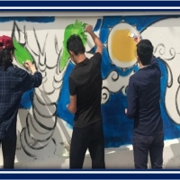 Children with their backs to the camera painting a mural