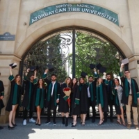 Graduates posing in front of a university