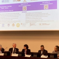 Photo of the panel - six speakers sit in a row with a presentation on a screen behind them