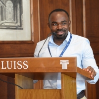 Bahati speaks at a lectern branded "LUISS"