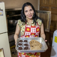 A lady shows a tray of baked goods.