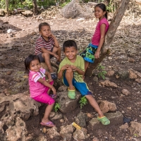 Four children play outside and smile for the camera.