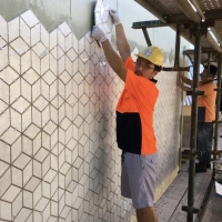 Man placing a tile in wall.