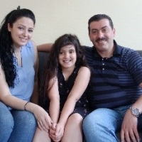 A woman, man and a child smiling at the camera sitting in a couch.