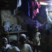 Family at a household in a camp setting, with light turned on.