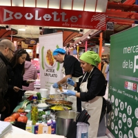 People being served food at a food market.