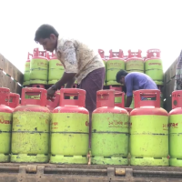Man in middle of gas containers on top of a truck.