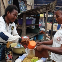 Ortense serving a customer at her market stall