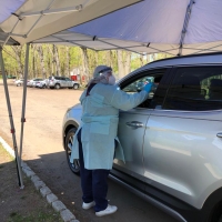 Iraqi refugee helps at a drive-thru coronavirus testing centre