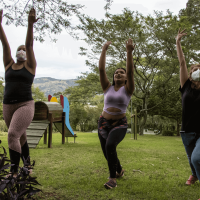 Three refugee women in a garden, telling their stories of teenage pregnancy through contemporary dance