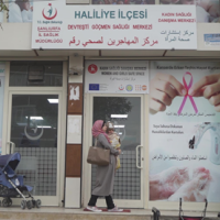 Woman walking past a Sexual and reproductive health centre with a baby.