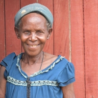 Soverinah Nyirazirahaga, a Congolese refugee in Uganda, stands in a doorway, smiling at the camera