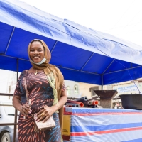 Diomade Manman, an urban refugee from Côte d’Ivoire, stands in front of her street food stall in Ajah market, Lagos state.