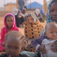 A woman and children seating in the ground.