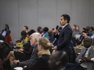 A man standing up in the audience of an event, speaking into a microphone