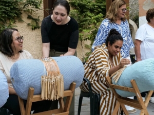 Women making lace demonstrate their craft to onlookers