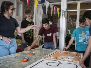 A group of youths working together to makes toy cars move.