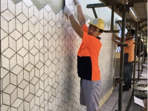 Man placing a tile in wall.
