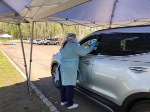 Iraqi refugee helps at a drive-thru coronavirus testing centre