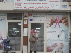 Woman walking past a Sexual and reproductive health centre with a baby.