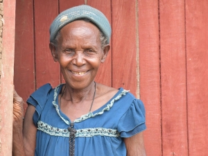 Soverinah Nyirazirahaga, a Congolese refugee in Uganda, stands in a doorway, smiling at the camera