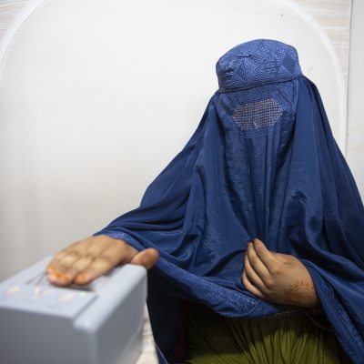 A woman wearing a burqa is having her fingerprints scanned