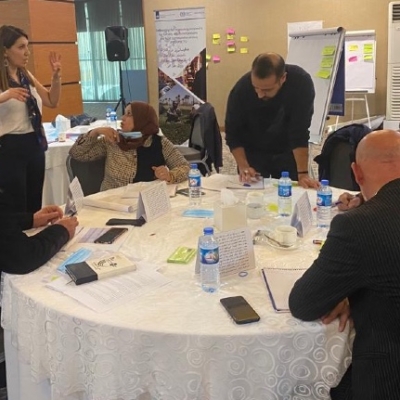 Participants in a discussion around a table speaking and making notes