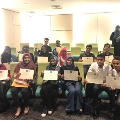 Students hold up their diplomat to the camera