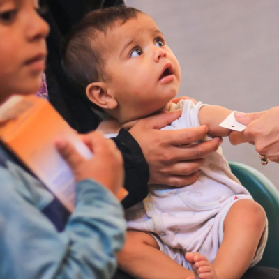 A very young child having the circumference of their arm measured
