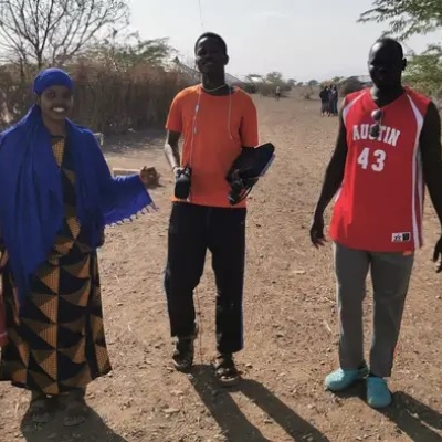 A woman and two men standing on a path, looking into the camera