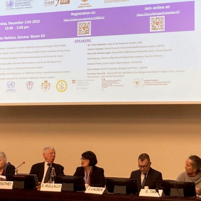 Photo of the panel - six speakers sit in a row with a presentation on a screen behind them
