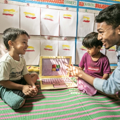 A man sits with two children with a fake laptop