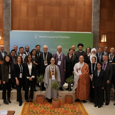 Religious representatives pose for a photo during the event ‘Religious Leaders Unite for Climate Peace in Solidarity with Refugees’, one of many discussions at the Global Refugee Forum 2023 - they are standing in a group facing the camera, with three potted trees in front of them.