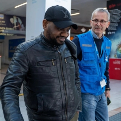 Two men walking together in the arrivals area of an airport.