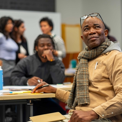 People sitting at a desk, a man holding a pen looks up
