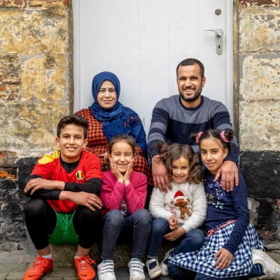 A family sitting on a porch, smiling and facing the camera