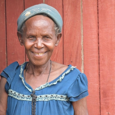 Soverinah Nyirazirahaga, a Congolese refugee in Uganda, stands in a doorway, smiling at the camera