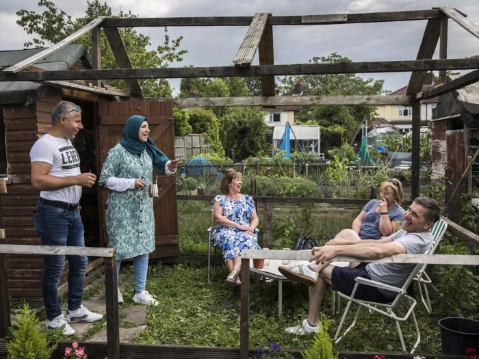 A group of people in an allotment laughing and talking