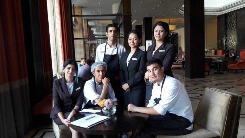 group of young people sitting at a table looking at the camera