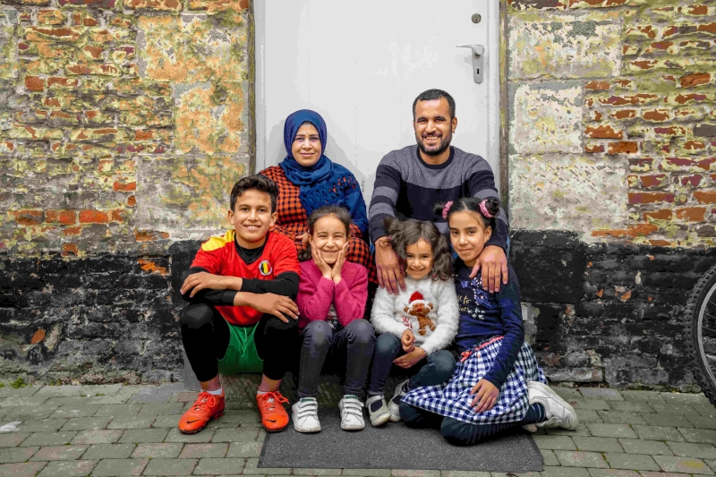 A family sitting on a porch, smiling and facing the camera