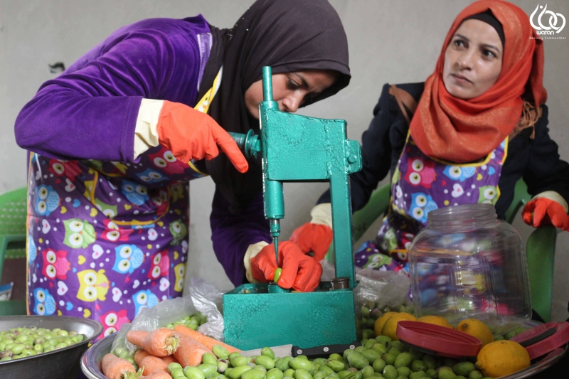 Two women are pitting olives