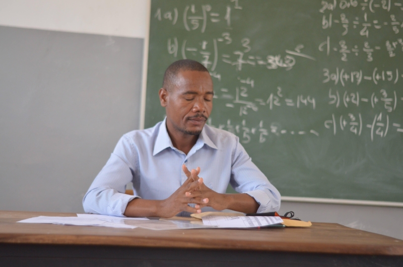 Man sitting at a desk in front of a black board