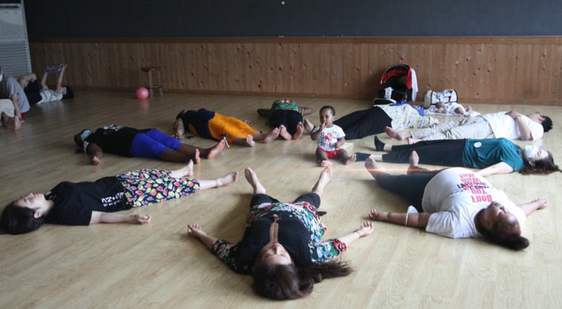 People laying on their backs a child sits in the middle of the circle
