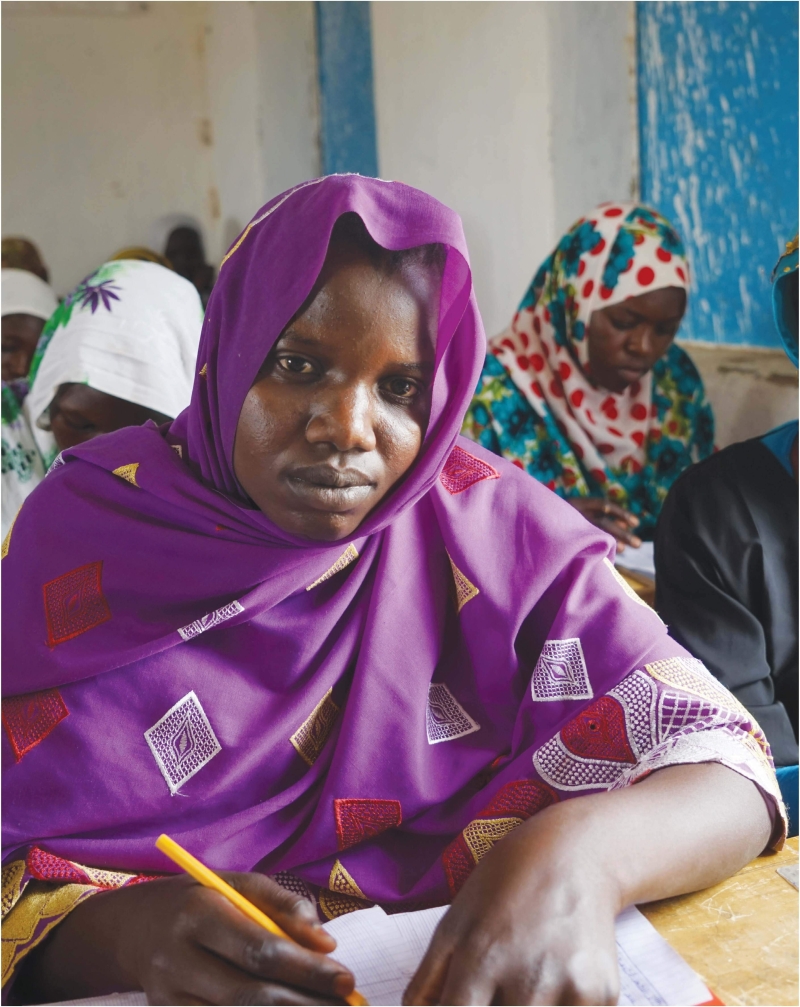 A woman in a classroom looks at the camera