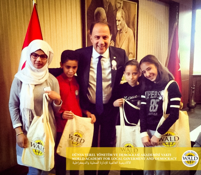 4 girls and a man smiling looking at the camera holding bags.