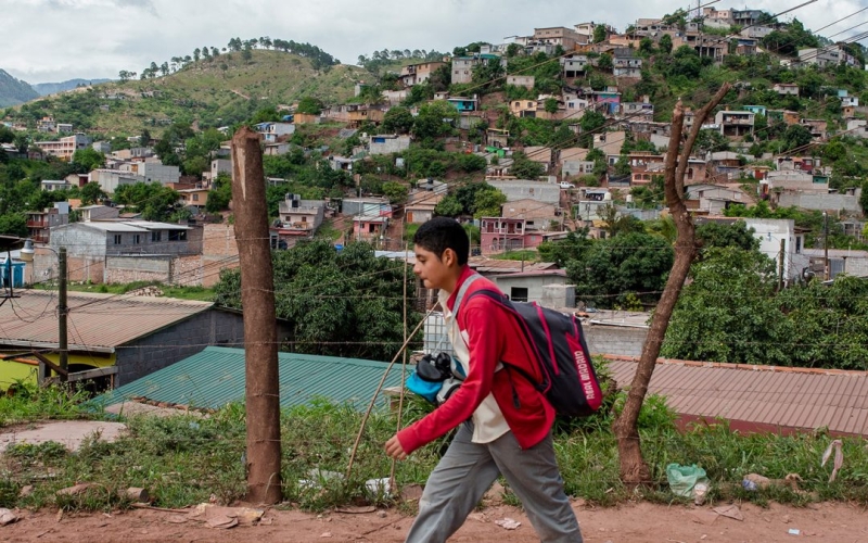 A boy walking along a path with a town in the background