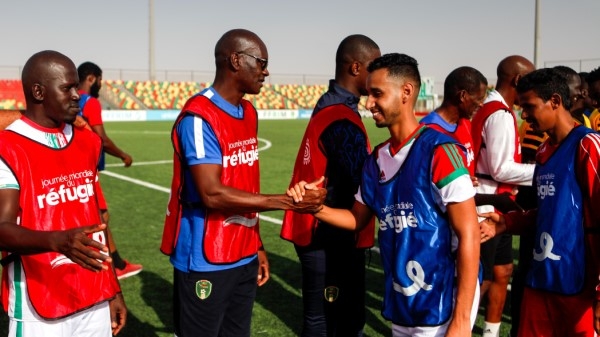 Two teams of footballers shake hands
